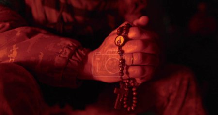 Foto de Los soldados rezan con rosarios en sus manos. Primer plano de las manos del vicario con rosario durante la oración. Rezaron por el tiempo militar. El hombre reza. - Imagen libre de derechos