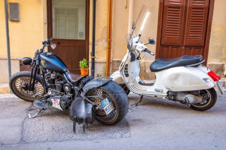 Téléchargez les photos : CASTELLAMMARE DEL GOLFO, ITALIE - 15 JUILLET 2023 : Harley Davidson et Vespa motos dans une rue. - en image libre de droit