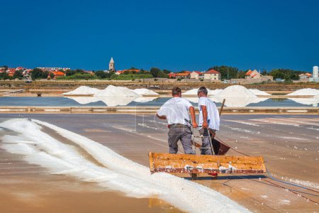 Photo for NIN, CROATIA - JULY 20, 2017: Men working in a ecological sea salt open factory. - Royalty Free Image