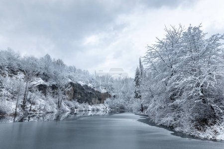 Photo for Winter snowy landscape with a lake by a rock wall. - Royalty Free Image