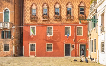 Foto de VENECIA, ITALIA - 3 de marzo de 2023: Señora con perros en la plaza de la ciudad. - Imagen libre de derechos