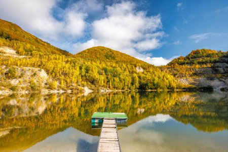 Téléchargez les photos : Paysage d'automne avec reflet de collines colorées dans le lac avec pilier d'embarquement. Carrière inondée près du village Sutovo en Slovaquie, Europe. - en image libre de droit