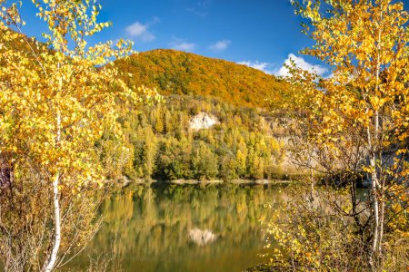 Téléchargez les photos : Paysage automnal avec un lac au bord des collines couvertes de forêts colorées. Carrière inondée près du village Sutovo en Slovaquie, Europe. - en image libre de droit