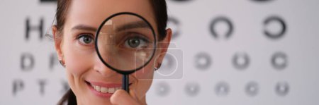 Photo for Doctor ophthalmologist looks through magnifying glass in ophthalmological clinic. Treatment of farsightedness myopia and astigmatism concept - Royalty Free Image