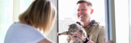 Foto de Hombre dando gato gris a mujer a través de la puerta. Sobreexposición del concepto de mascotas - Imagen libre de derechos