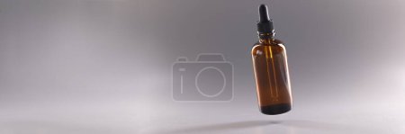 Photo for Close-up of glass bottle filled with liquid, flask with cosmetology or medical product. Moisturizer lotion or oil for body and face. Cosmetology and wellness - Royalty Free Image