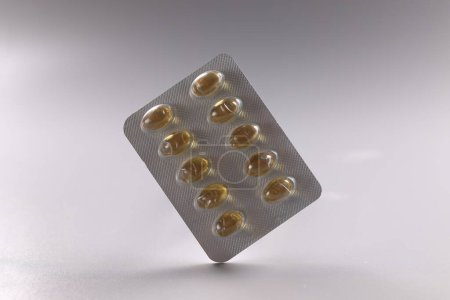 Foto de Fish oil Omega 3 tablets in blister pack with capsules on gray background. Vitamins medicine and supplements concept - Imagen libre de derechos