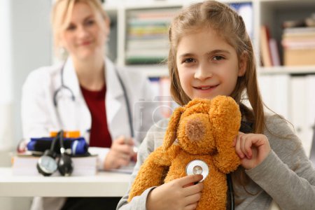 Foto de Doctor and child with toy and stethoscope in clinic. Medical insurance and pediatrician services - Imagen libre de derechos