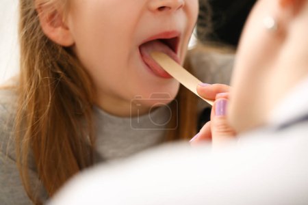 Téléchargez les photos : Otorhinolaryngologist examines child girl with sore throat. Treatment of throat in children and pharyngitis concept - en image libre de droit