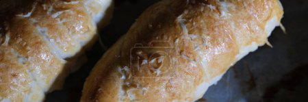 Téléchargez les photos : Freshly cooked sausage sausage in dough with white sauce on baking sheet. Cooked bun roll with stuffing concept - en image libre de droit