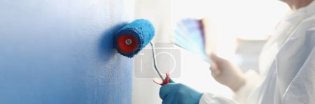 Photo for Painting white wall with blue roller. Services of master painter for home repair - Royalty Free Image