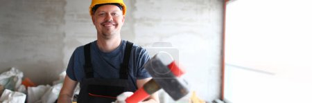 Photo for Male builder holds sledgehammer hammer at construction site. Construction services and demolition of apartment walls concept - Royalty Free Image