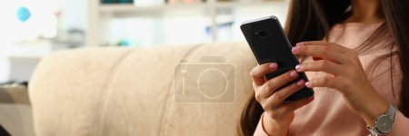 Photo for Woman using smartphone sitting on sofa at home. Communication in social networks using Internet and online shopping - Royalty Free Image