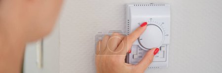 Hand adjusts button of the control unit of heating and cooling system of house closeup. Home or office climate control