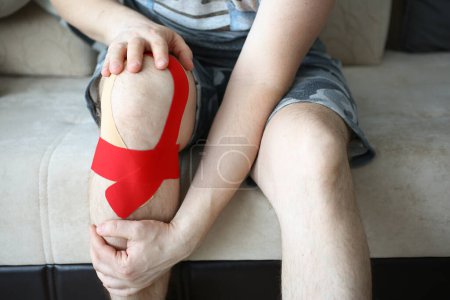 Photo for Sick man knee is sealed with kinesio tape. Treatment of injuries and sprains of the knee joint concept - Royalty Free Image