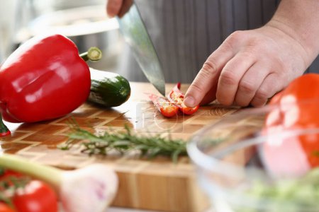 Téléchargez les photos : Chef coupe les piments à bord en gros plan. Cuisiner des légumes et des aliments végétaliens avec des épices concept - en image libre de droit