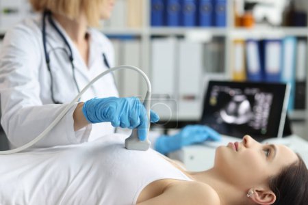 El médico sostiene la sonda de ultrasonido en el pecho del paciente en el primer plano de la clínica. Examen médico de mama en la clínica