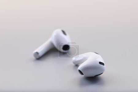 Foto de Auriculares inalámbricos blancos con estilo bluetooth sobre fondo gris. Auriculares para escuchar música - Imagen libre de derechos