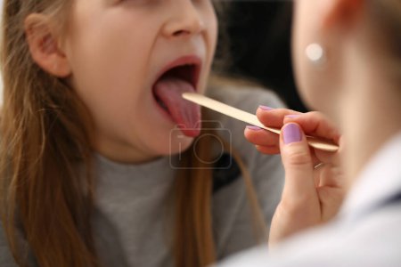 Photo for Doctor conducts medical examination of sick red throat of little girl. Angina in children concept - Royalty Free Image