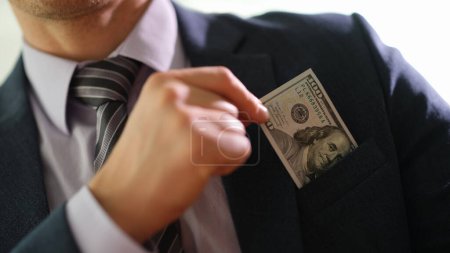 Businessman taking hundred dollar bill out of jacket pocket closeup. Bribery in business concept