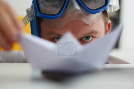 Foto de Joven con gafas de natación juega con papel en el lugar de trabajo. Concepto de venta de entradas para cruceros de idea turística - Imagen libre de derechos