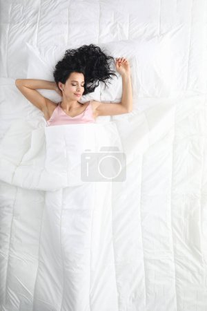 Beautiful woman sleeping serenely in bed top view. Sound healthy sleep and comfort concept