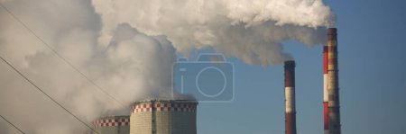 Foto de CHP cooling towers from which smoke is coming out against blue sky. Combined thermal power plant concept - Imagen libre de derechos