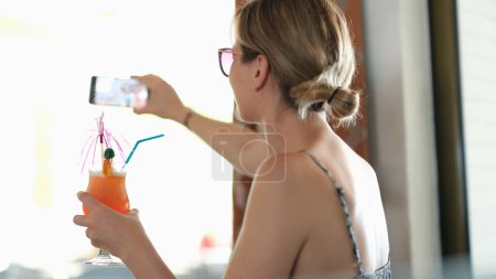 Téléchargez les photos : Femme tient un cocktail, prend selfie pris sur téléphone portable. Vacances d'été dans le café - en image libre de droit