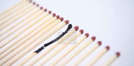 Photo for Close-up view of one wooden burnt match among many new whole. Conceptual image of non-renewable energy. Burn out syndrome and stress concept. Isolated on white background - Royalty Free Image