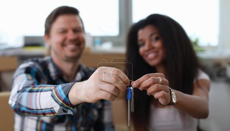 Photo for Focus on people hands holding keys of new apartment. Man and woman smiling and looking happy about relocation to house. Real estate and changing of living place concept - Royalty Free Image