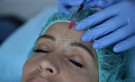 Foto de Retrato de una mujer que recibe una inyección entre las cejas. Inyecciones de cejas para concepto de eliminación de arrugas - Imagen libre de derechos