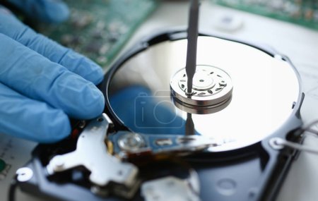 Photo for Male repairman wearing blue gloves dismantles specialized professional screwdriver hard drive. Performs fault diagnostics and performs urgent repairs recovery of lost data during deletion HDD closeup - Royalty Free Image