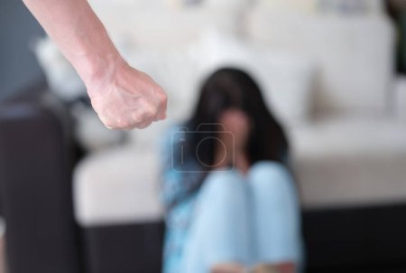 Foto de El hombre está de pie con el puño apretado contra el fondo de la mujer llorando. Violencia doméstica y concepto de grosería masculina - Imagen libre de derechos