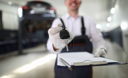 Photo for Focus on automechanic male hand holding important paper tablet with information about fixed auto and automobile distant opener. Machinery checkup concept. Blurred background - Royalty Free Image