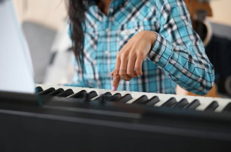 Foto de Centrarse en la mano femenina jugando sintetizador en el estudio de música. Profesional pianista lindo aprender nueva composición musical. Concepto de arte y música. Fondo borroso - Imagen libre de derechos