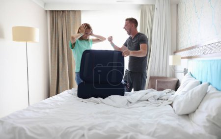 Téléchargez les photos : Homme et femme se battent dans la chambre près de la valise. - en image libre de droit