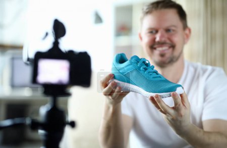 Photo for Close-up of smiling middle-aged man filming red sneaker on camera and tell in vlog. Male describing quality of new boots on display of digital device. Technology and blogger concept - Royalty Free Image