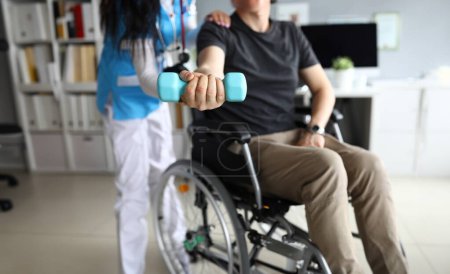 Close-up of patient in wheelchair at procedures of physiotherapist. Rehabilitation after injury. Doctor in uniform helping man. Healthcare and medicine concept
