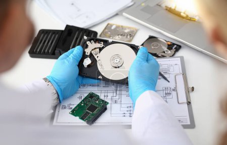 Technician repairs computer hard drive from motherboard. Hard drive diagnostic services concept