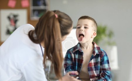 Photo for Doctor consults little boy with sore throat. Inflammation of tonsils of adenoids and tonsillitis in children - Royalty Free Image
