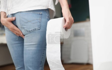 Téléchargez les photos : L'homme se tient devant les toilettes et tient du papier toilette. Concept d'endoscopie Symptômes - en image libre de droit