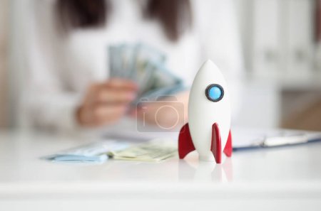 Photo for Close-up of rocket model on desk, rocketship symbol for startup, earn money on beneficial project. Success, growth, development, wealth, income concept - Royalty Free Image