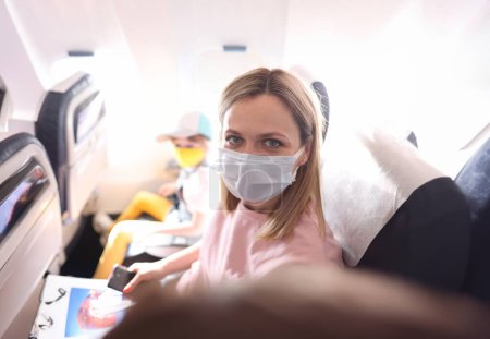 Téléchargez les photos : Jeune femme en masque de protection faisant selfie dans la cabine de l'avion. Règles de vol pour les passagers pendant la covid19 concept de pandémie - en image libre de droit