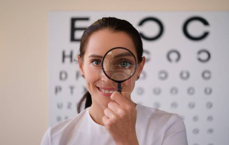 Photo for Doctor ophthalmologist looks through magnifying glass in ophthalmological clinic. Treatment of farsightedness myopia and astigmatism concept - Royalty Free Image