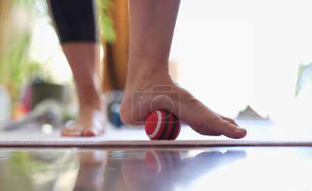 Photo for Man massages feet with small ball. Therapeutic massage of the lower extremities. Exercises for foot massage and myofascial therapy. - Royalty Free Image
