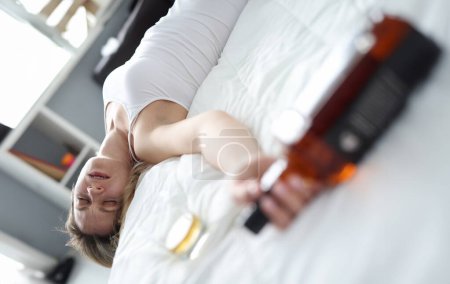 Photo for Drunk woman sleeping with bottle of alcohol in bed. Female alcoholism concept - Royalty Free Image