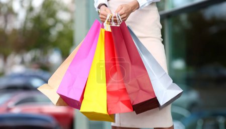 Téléchargez les photos : Femme debout près de magasin de robe tenant dans les mains pile de sacs en papier multicolore gros plan - en image libre de droit