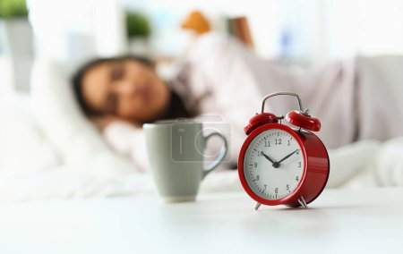 Téléchargez les photos : Belle femme indienne paisiblement couchée au lit dormant tôt le matin tandis que le réveil sonne. Réveil précoce, manque de sommeil, sommeil excessif, concept de temps de travail - en image libre de droit