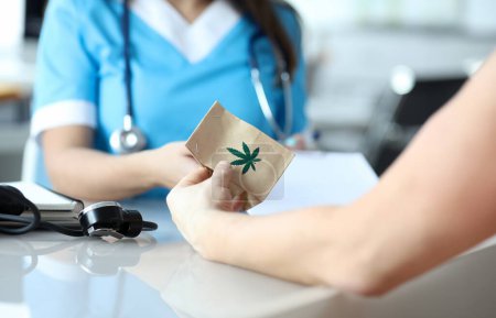 Téléchargez les photos : Une femme médecin écrit une ordonnance de marijuana médicale au patient au bureau de l'hôpital. Concept légal de traitement de la marijuanna - en image libre de droit
