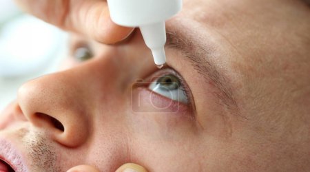Photo for Man putting liquid drops in his eye solving vision problem closeup - Royalty Free Image